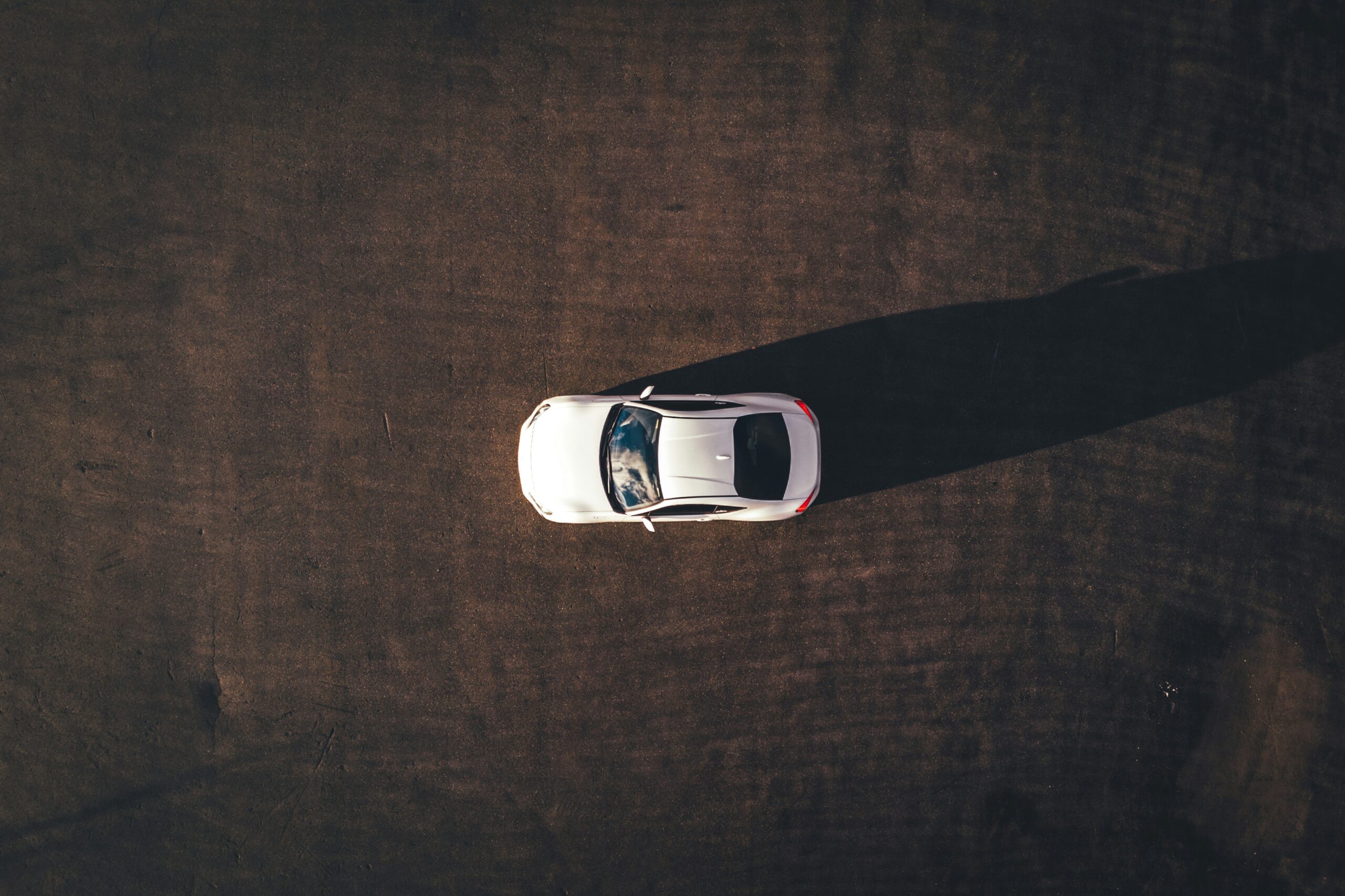 Ein weißes Auto steht allein auf einem leeren Parkplatz, ideal für GPS Ortung und Fahrzeugortung.